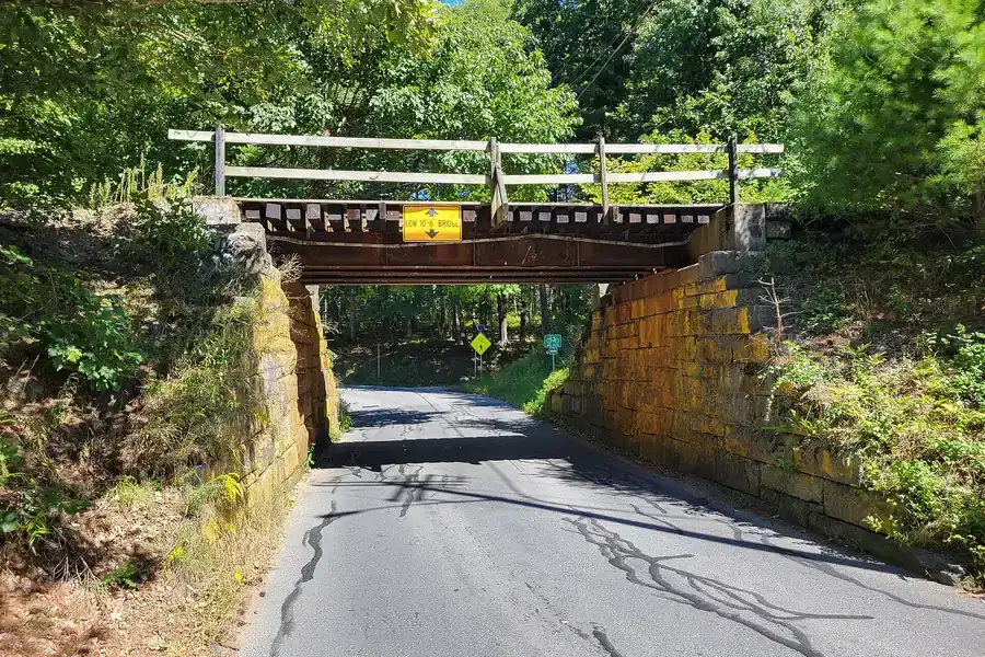 Old railroad bridge over North Washington Street among summer trees in Belchertown, Massachusetts