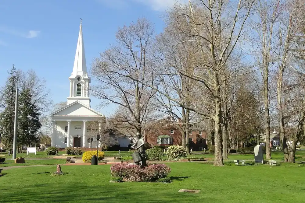 Village green with a white church steeple and spring trees in Bloomfield, Connecticut