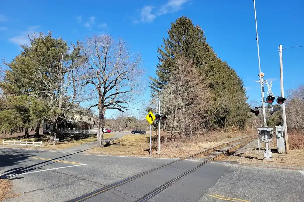 Railroad crossing on State Street lined with tall pines in Palmer, Massachusetts