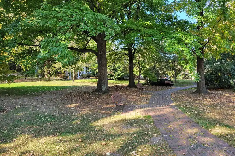 Brick path under tall shade trees in Schultz Park, Simsbury, Connecticut