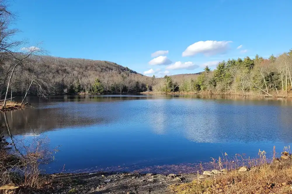 Hurds Lake under a blue sky with wooded hills in Somers, Connecticut