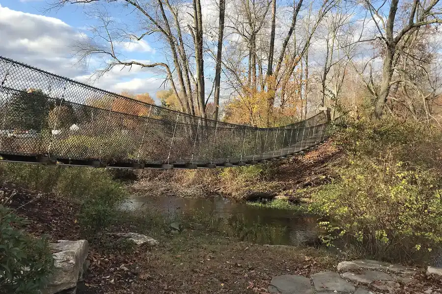 Suspended footbridge over the Hockanum River on a wooded trail in Vernon, Connecticut