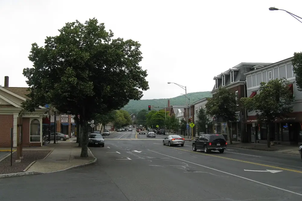 Tree-lined Main Street with brick storefronts and distant hills in Ware, Massachusetts