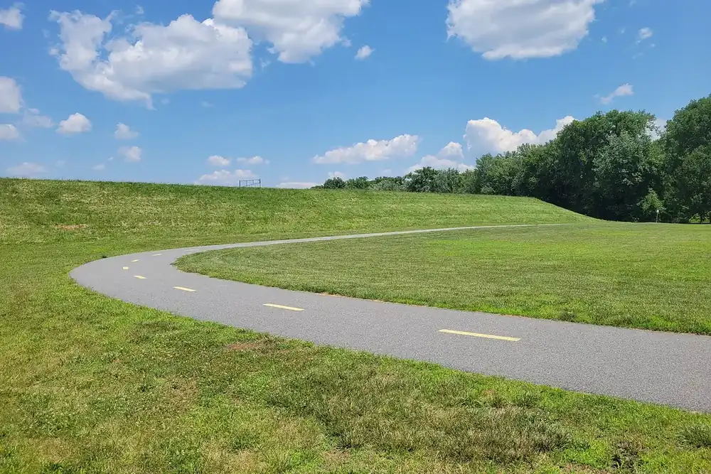 Curving paved bikeway along the grassy Connecticut River dike in West Springfield, Massachusetts